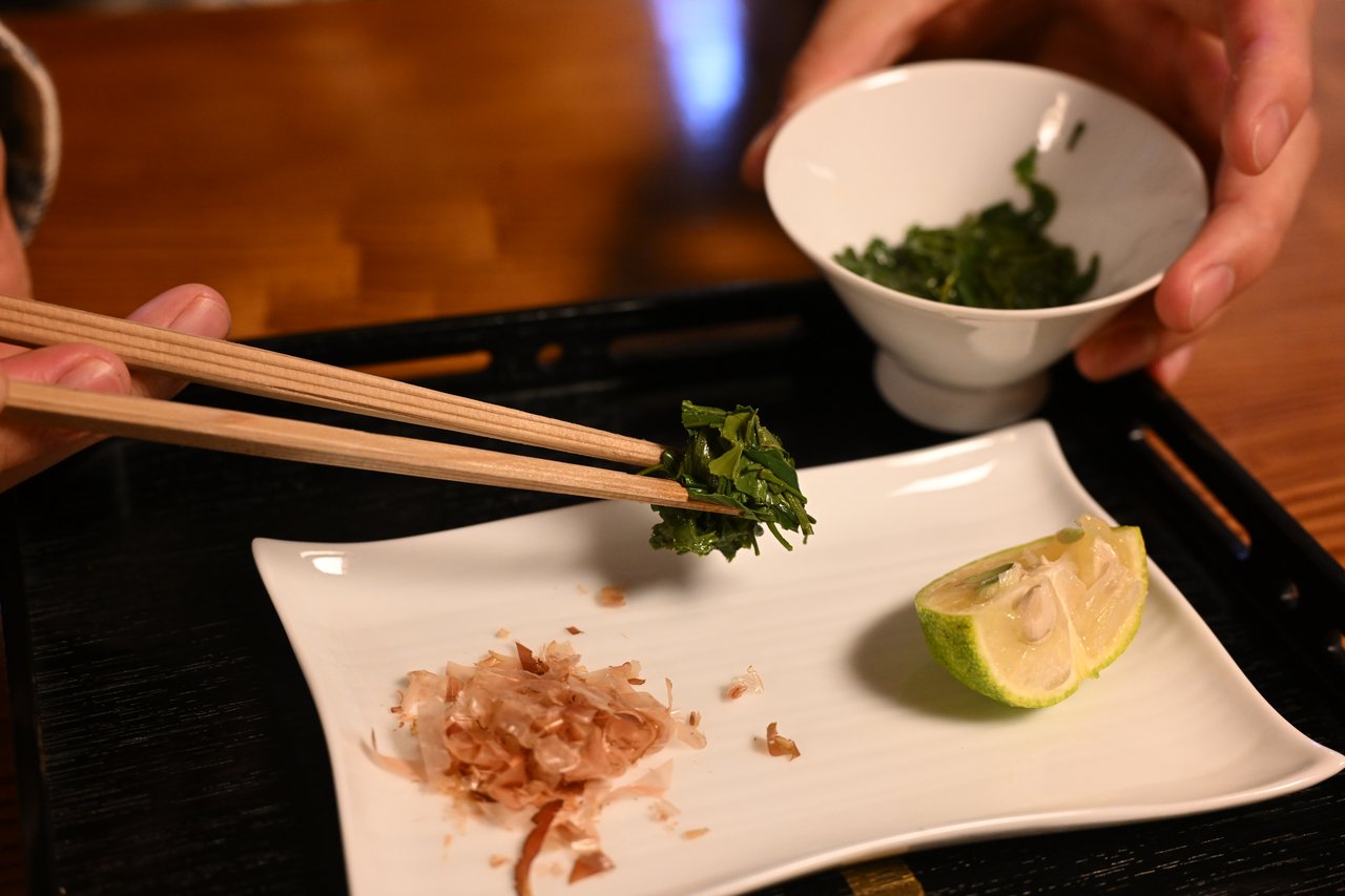 Steeped premium green-tea leaves seasoned with bonito and citrus, eaten with chopsticks at a tea café
