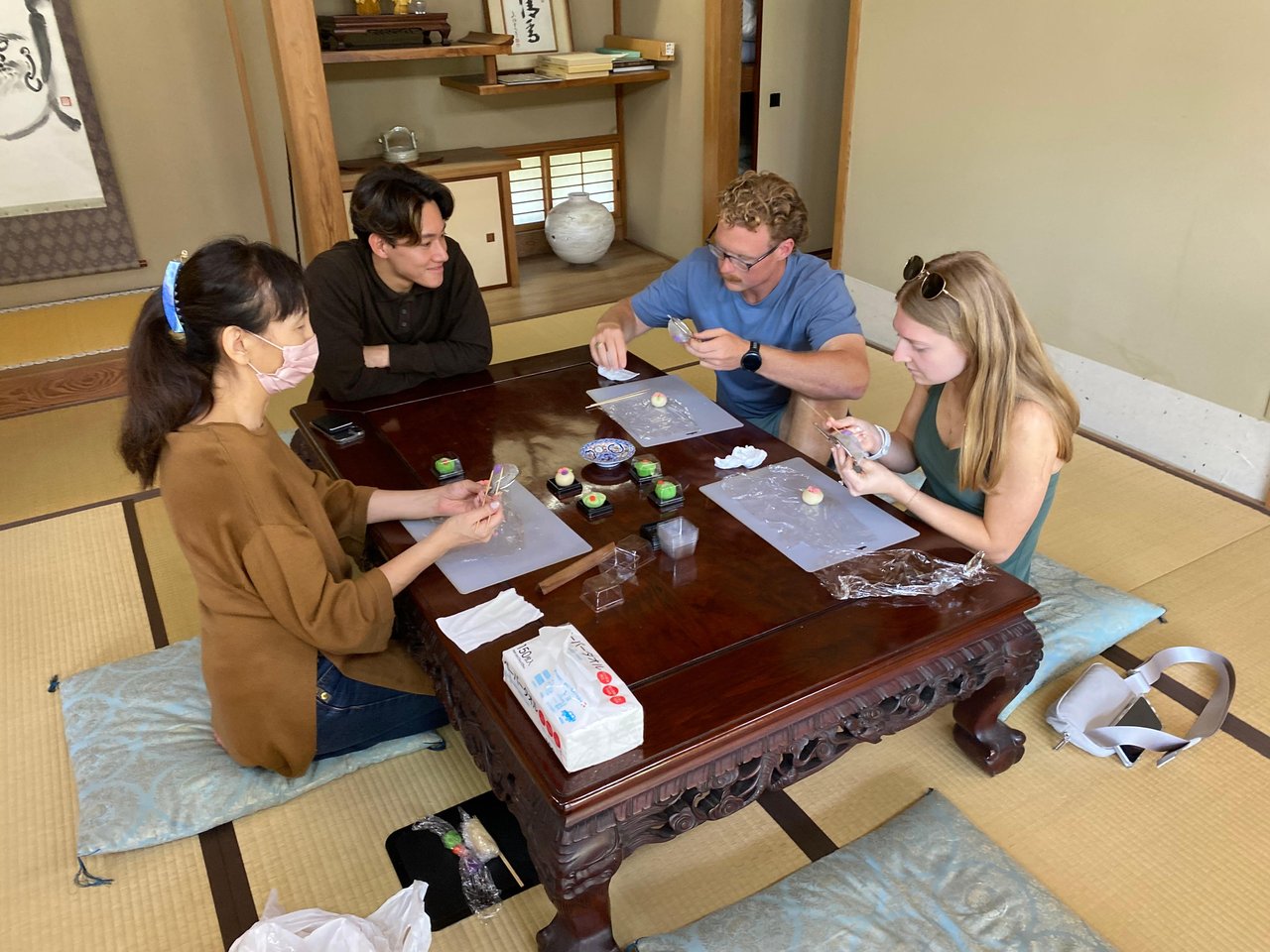 Guests shaping seasonal wagashi sweets with an instructor in a tatami room