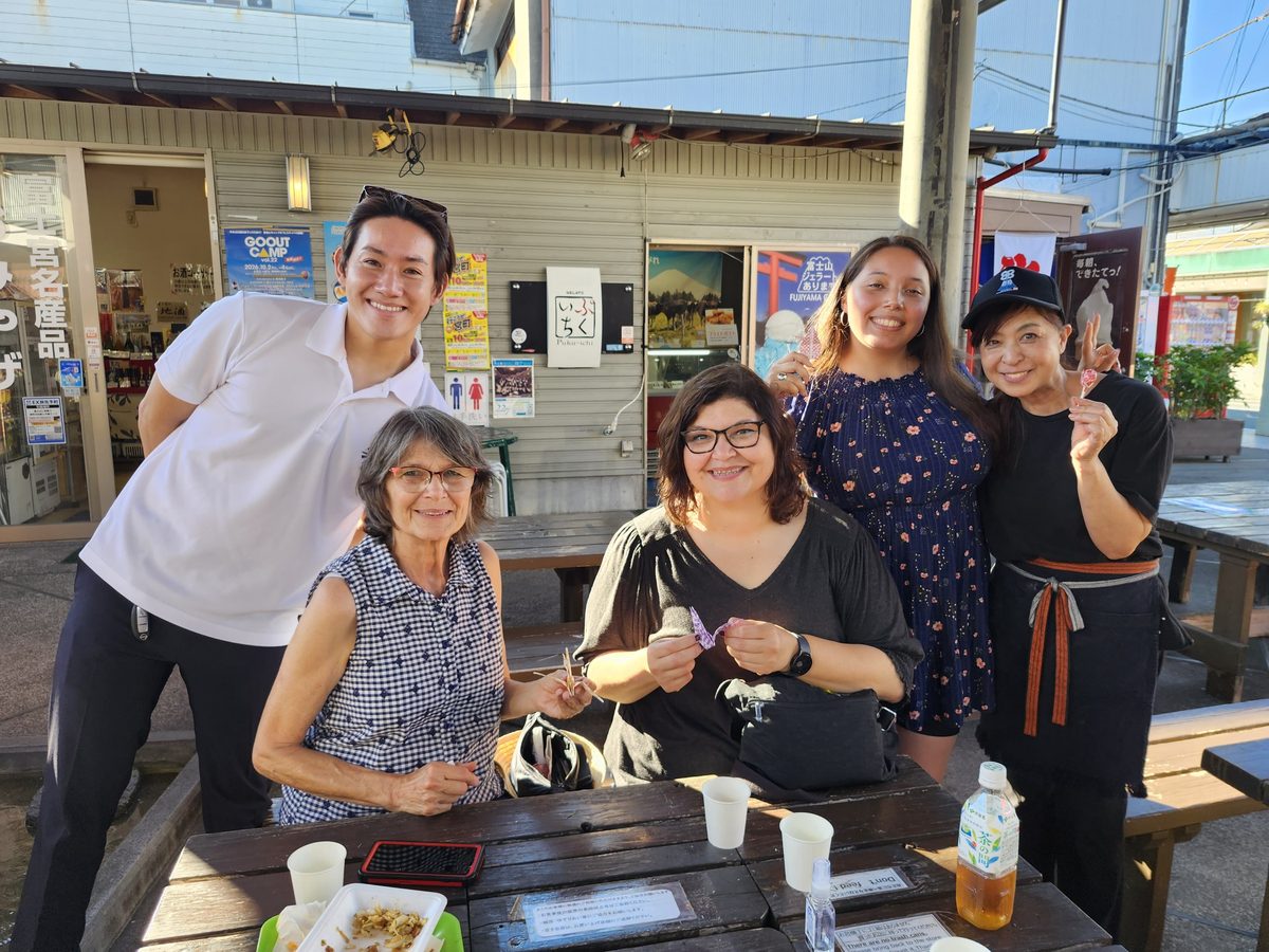Guests holding origami paper cranes with their guide and a local