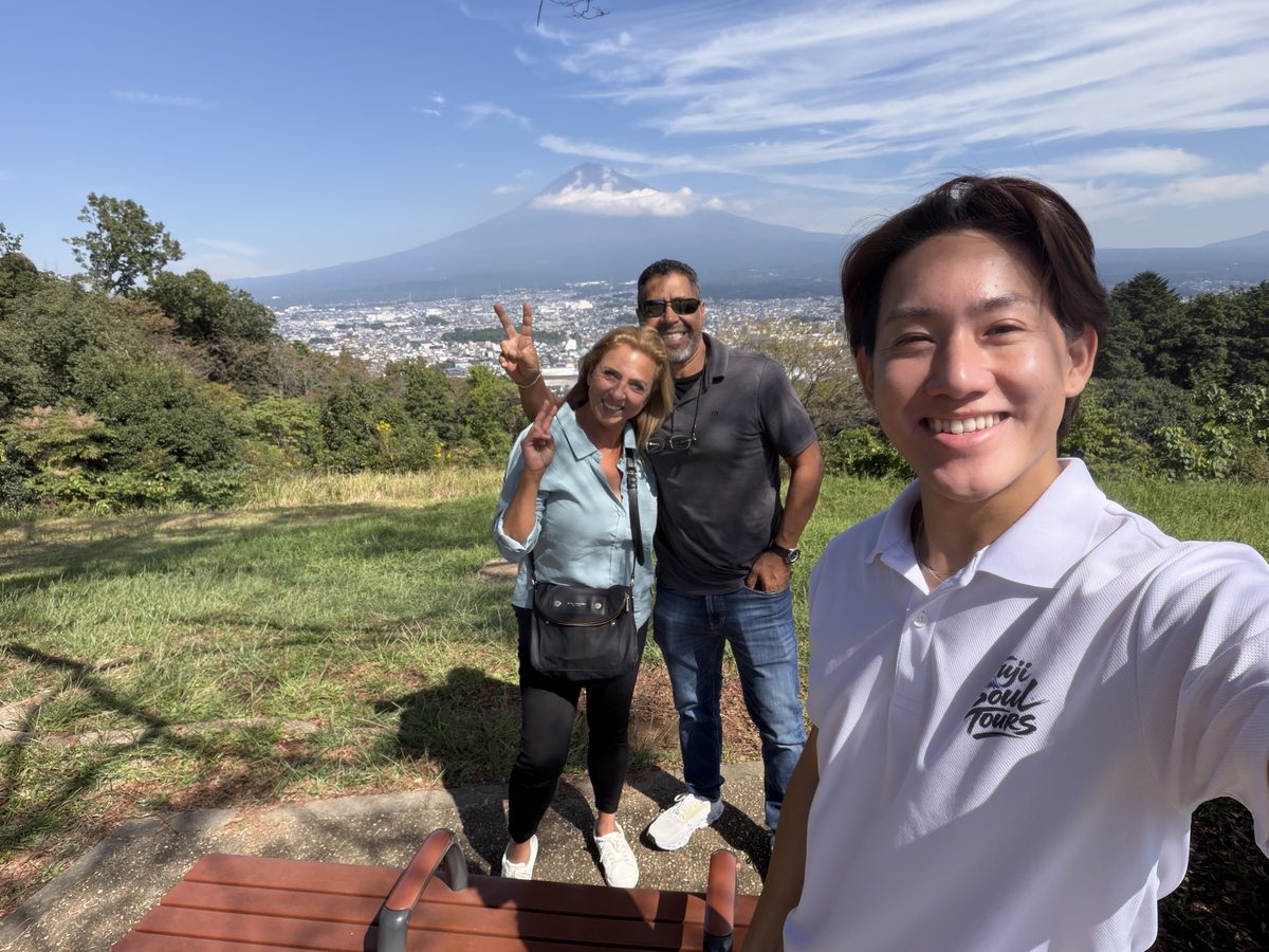 Guests and their guide at a hilltop viewpoint with Mt. Fuji above the city