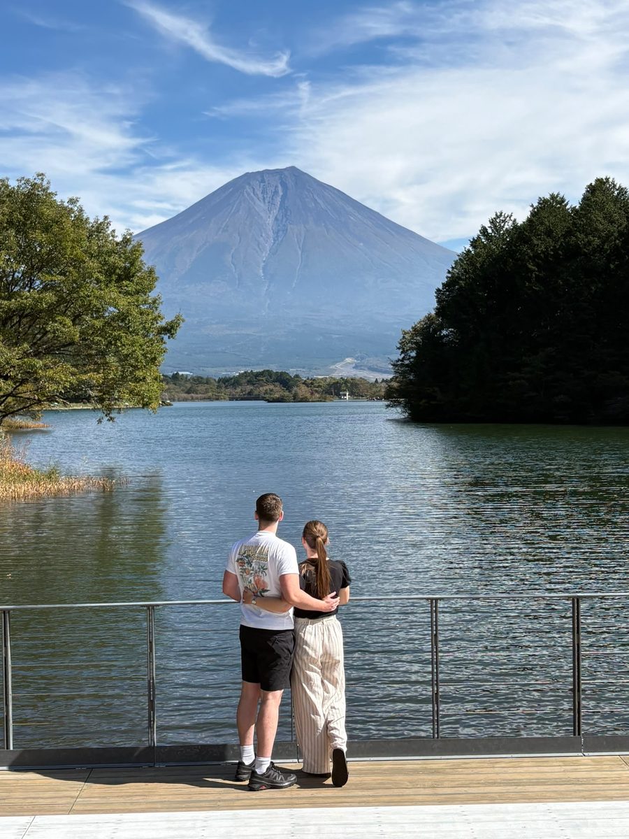 Couple on a lakeside deck looking at Mt. Fuji across the water