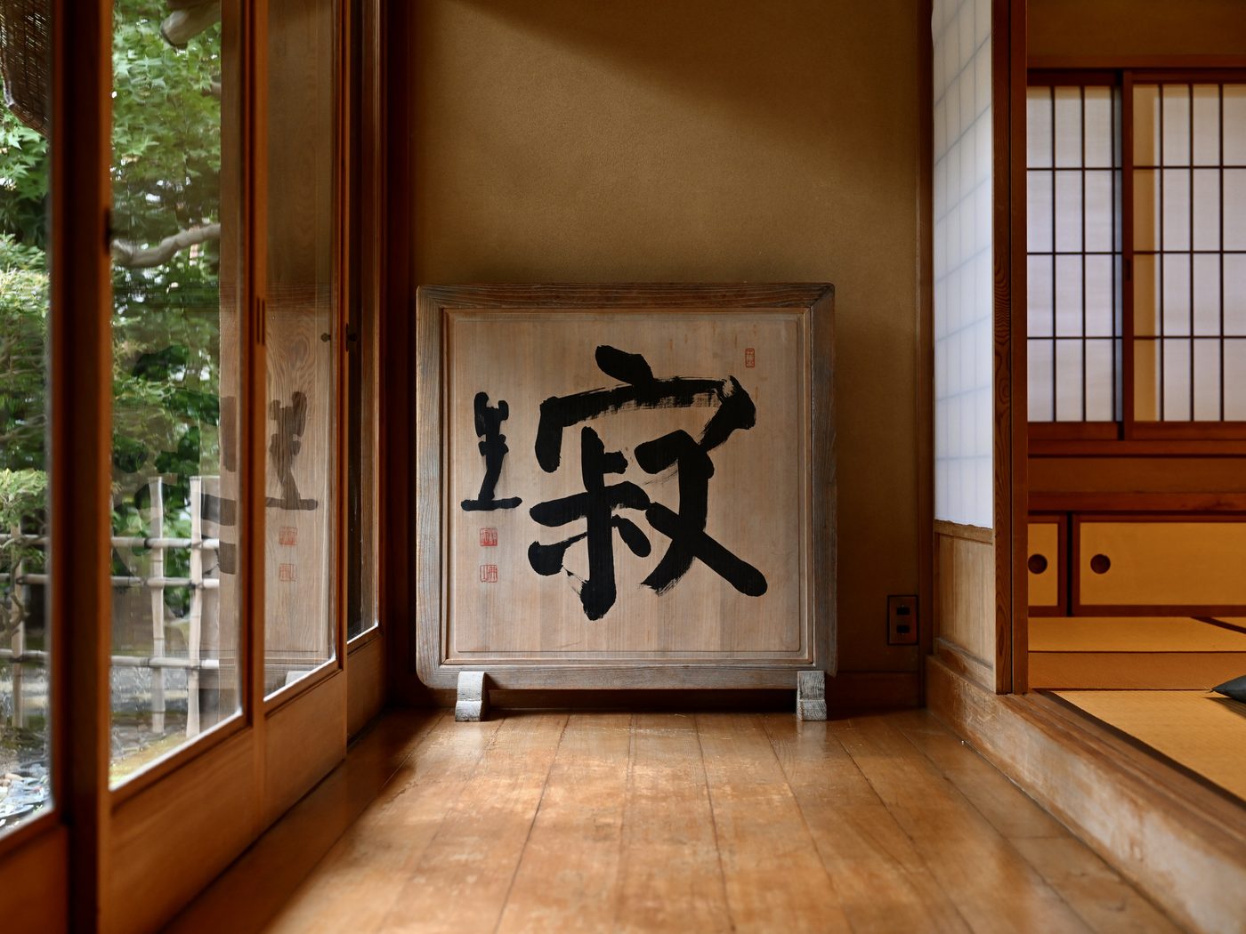 A quiet tatami room with a folding screen reading jaku, meaning stillness