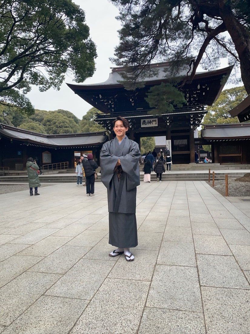 Takumu, founder of Fuji Soul Tours, in a kimono offering a respectful bow at a shrine gate