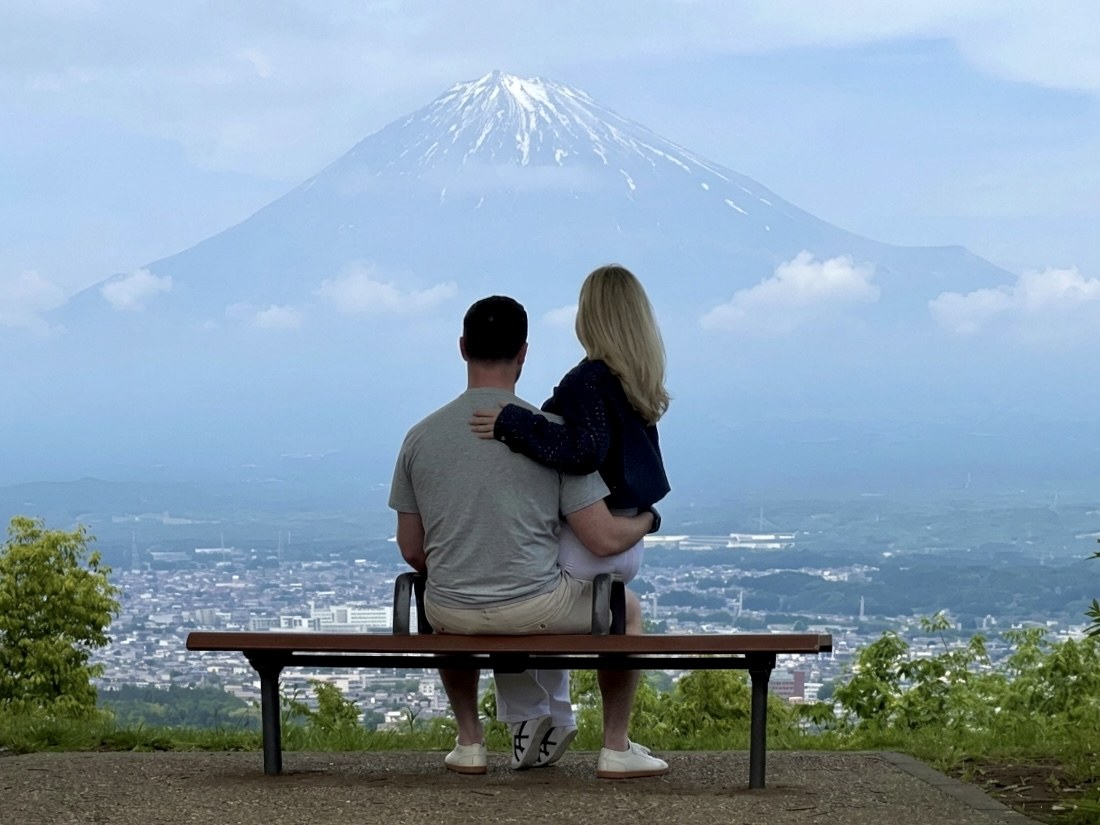 Two travelers sitting together and looking toward snow-capped Mt. Fuji