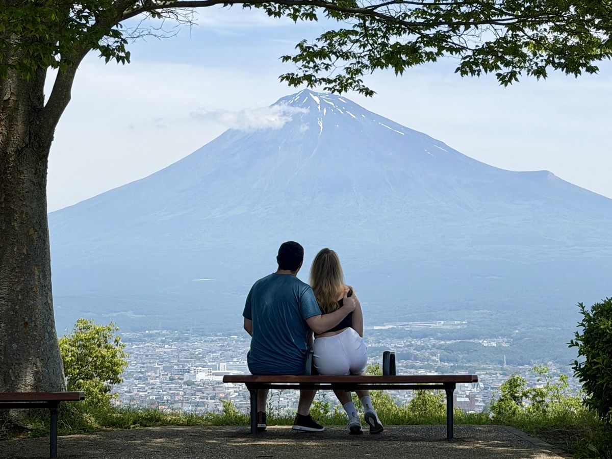 Couple watching Mt. Fuji from a park bench viewpoint