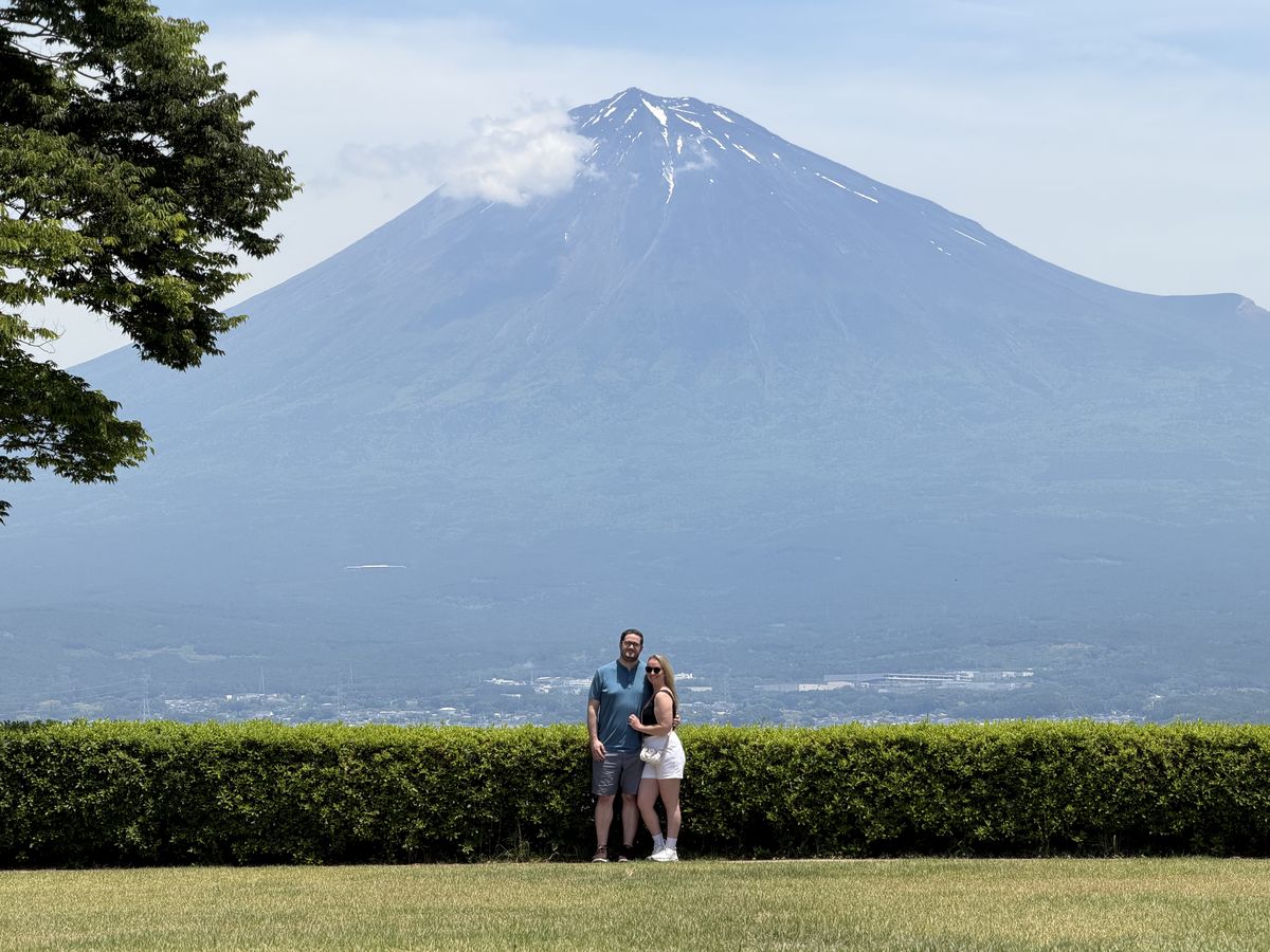 Two guests standing on a quiet park lawn in front of Mt. Fuji