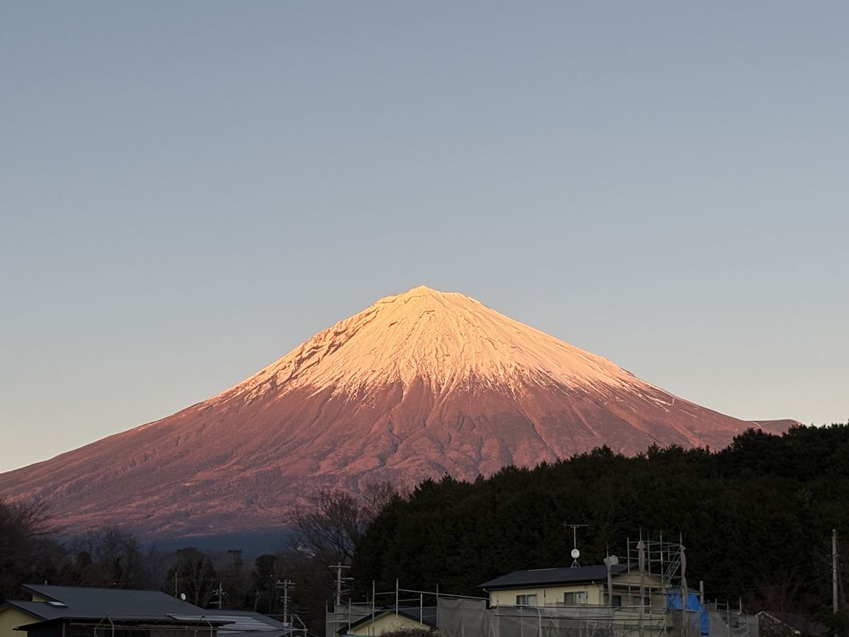 Dawn light turning Mt. Fuji's snowcap red above neighborhood rooftops
